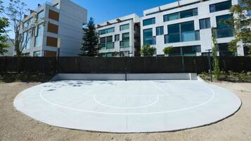 Una cancha de baloncesto al aire libre con una vista despejada de edificios modernos al fondo.