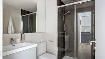 A modern bathroom with a glass-enclosed shower, a white sink, and a toilet.