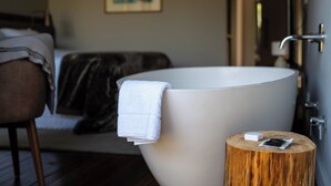 A modern bathroom with a large bathtub, a wooden stool, and a towel. - Fazenda Bom Retiro Hotel Boutique (Bom Retiro)