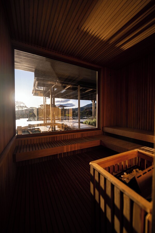 A wooden interior with a large window, wooden benches, and a small pool area.