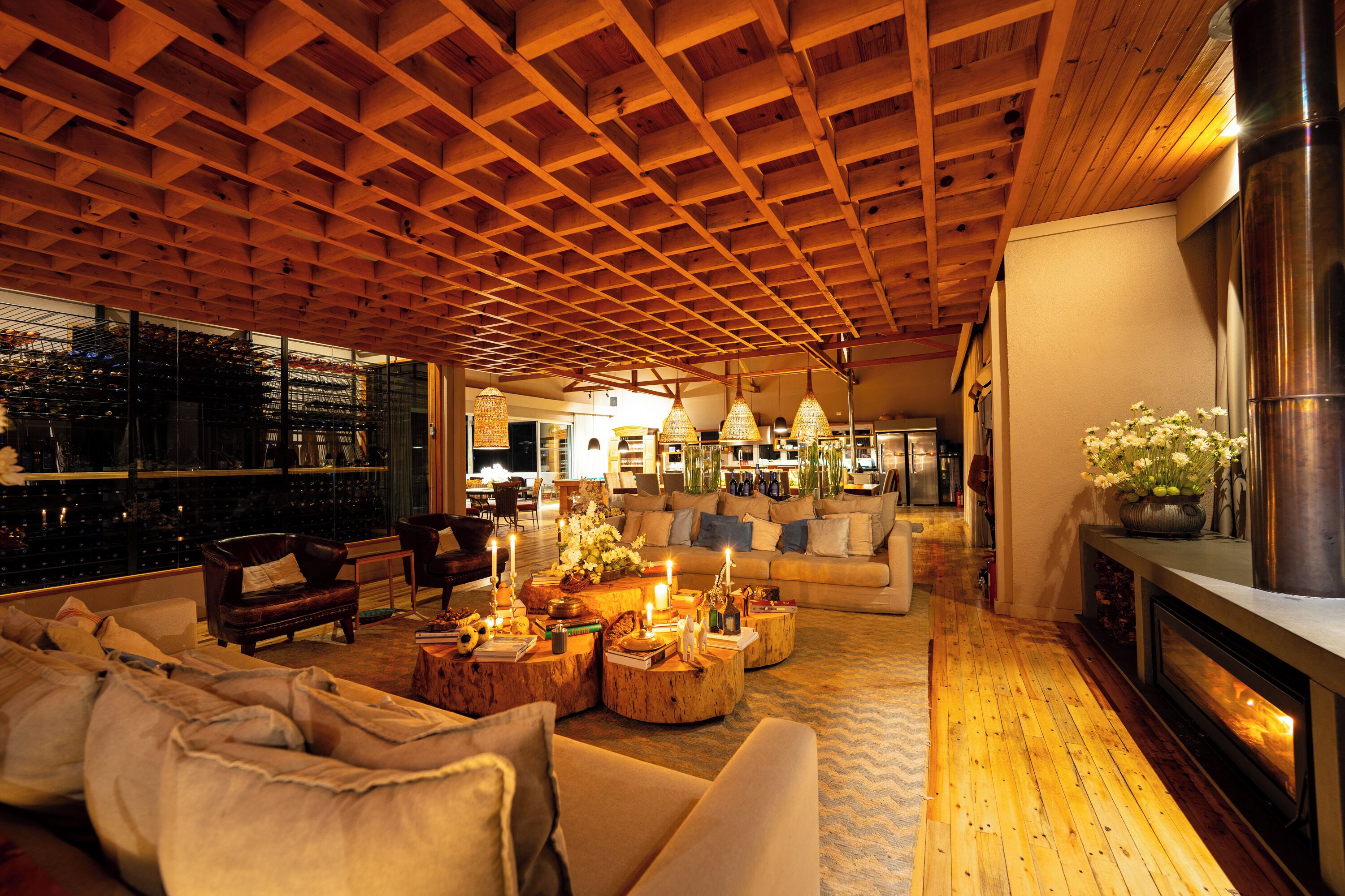 A spacious living area with a high wooden ceiling, a fireplace, and a view of the city through large windows.