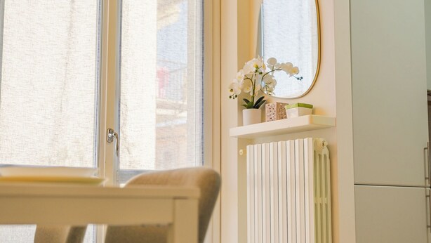 A room with a window, a radiator, a mirror, and a shelf with flowers. - Casa Sophie - One Bedroom Apartment, Sleeps 4 (Desenzano del Garda)