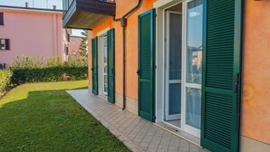 A residential building with green shutters, a paved pathway, and a well-maintained lawn. - Casa Sophie - One Bedroom Apartment, Sleeps 4 (Desenzano del Garda)