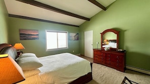 A bedroom with a bed, dresser, and a window.