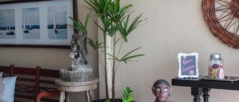 Una habitación acogedora con un banco de madera, una pequeña mesa con una estatua y un estante en la pared con objetos decorativos.
