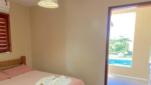 A bedroom with a bed, a window, and a door leading to a balcony. - POUSADA MUCURIPE (Fortaleza)