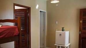 A room with a bunk bed, a small white refrigerator on a stand, and a door with a number. - POUSADA MUCURIPE (Fortaleza)