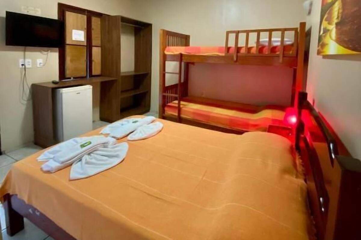 A room with a bunk bed, a desk, a television, and a bed with towels.