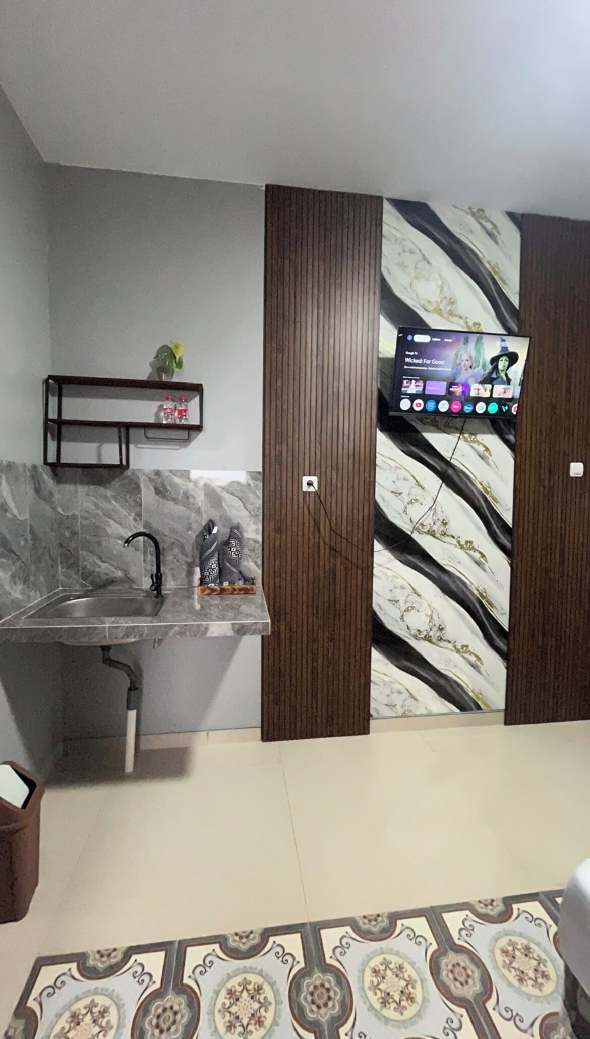 A modern kitchen with a marble backsplash, a built-in sink, and a wooden cabinet with a tree branch design.