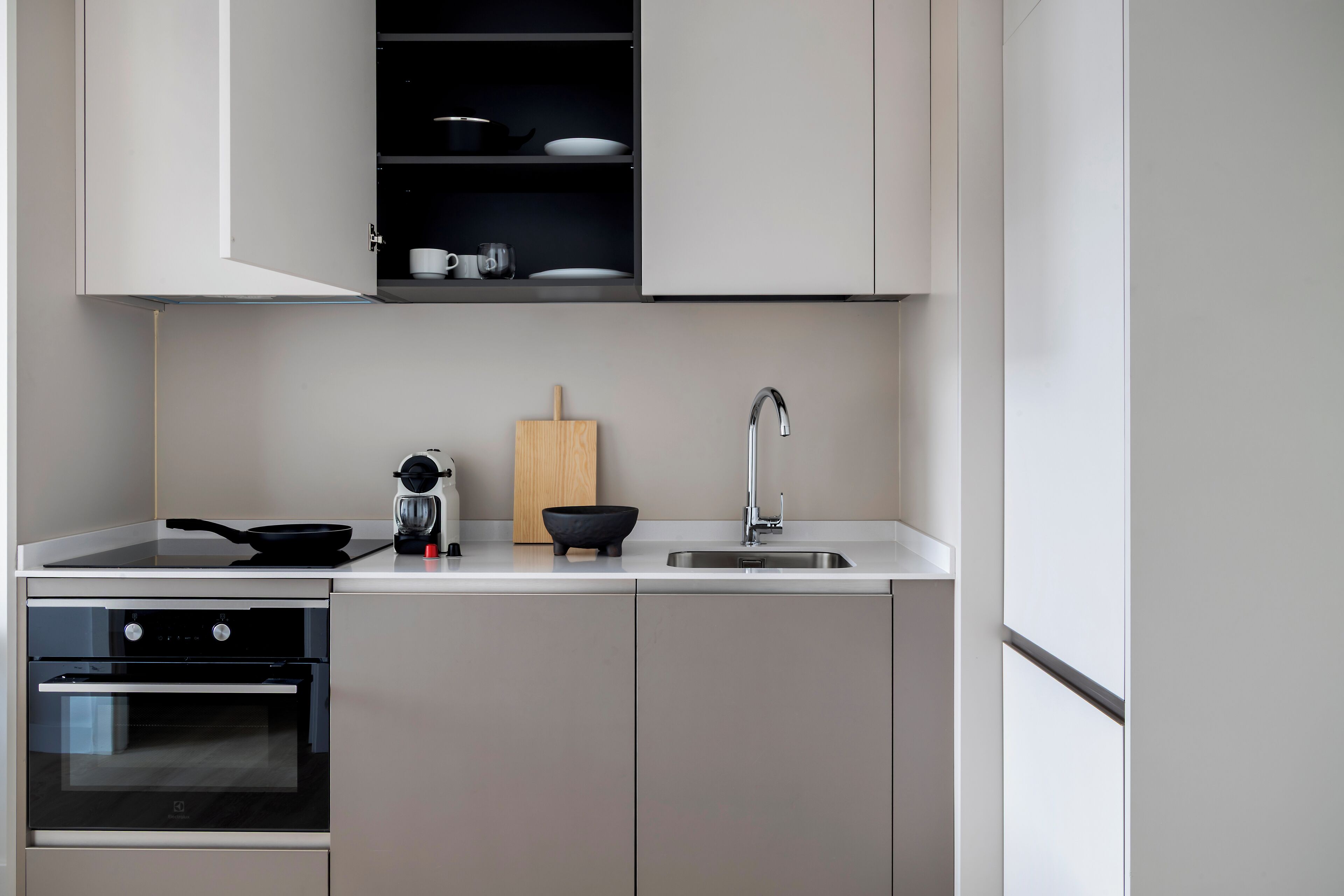 Una cocina moderna con horno empotrado, estufa, lavaplatos y tabla de cortar de madera.