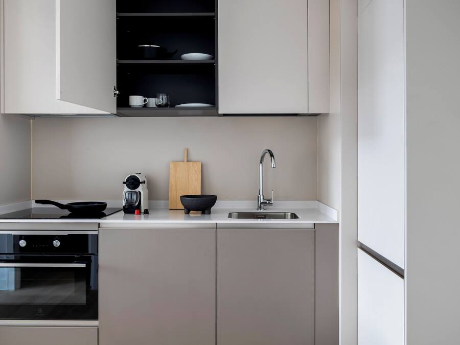 Una cocina moderna con horno empotrado, estufa, lavaplatos y tabla de cortar de madera.