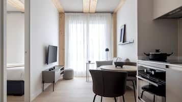Una cocina moderna con comedor, televisor y un amplio ventanal con cortinas ligeras.