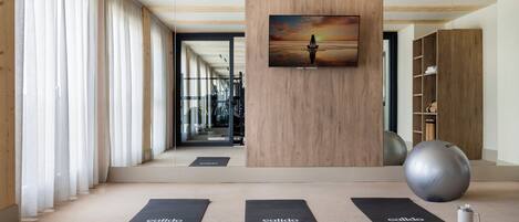 A modern gym with exercise mats, a large exercise ball, and a motivational painting on the wall.