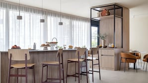 Una cucina moderna con sgabelli da bar in legno, un'isola integrata e un'area pranzo con sedie.