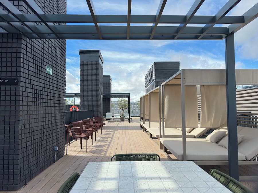 Terraço no telhado com pérgola, área de estar e vista para a paisagem urbana.