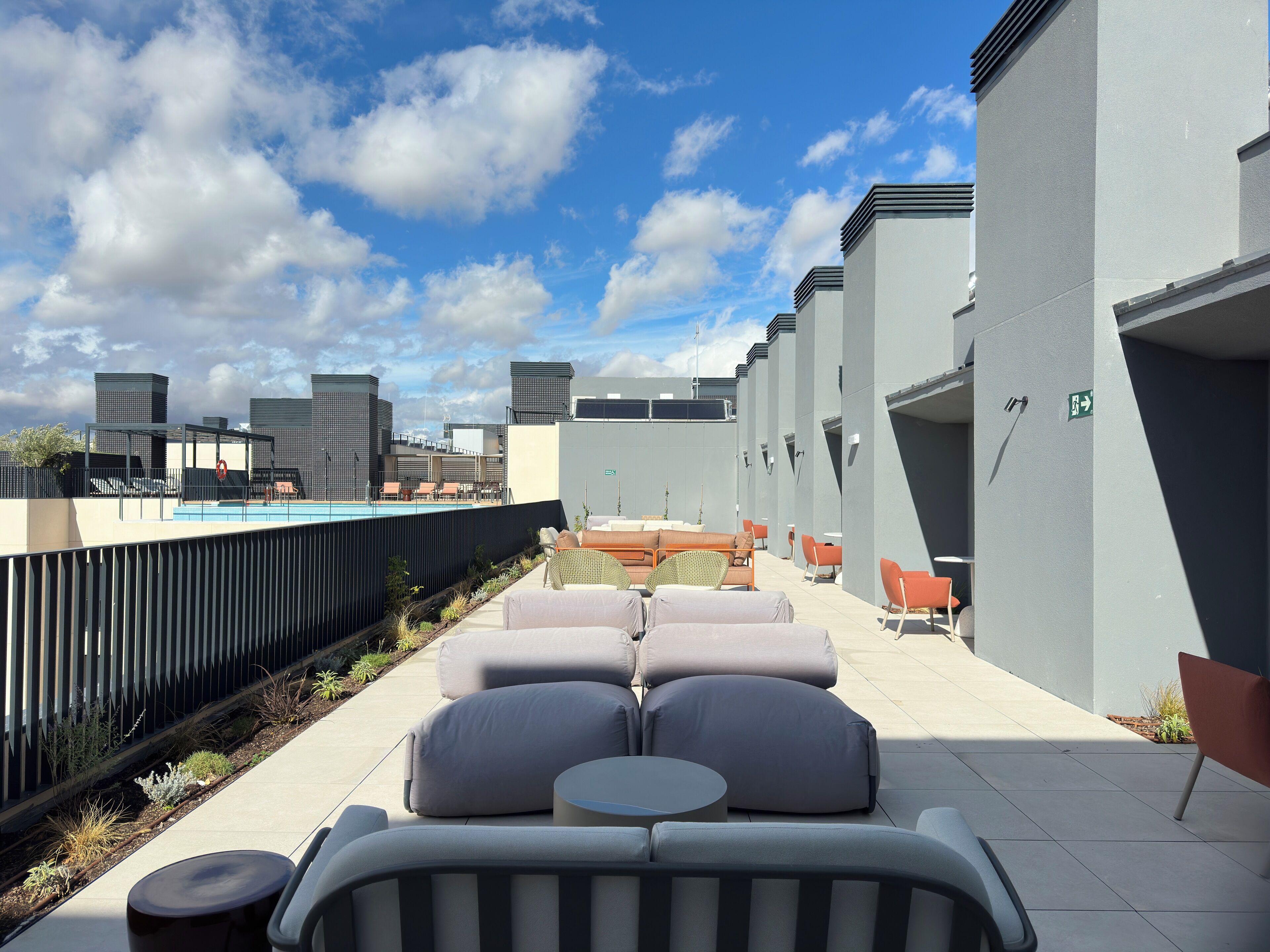 A rooftop terrace with a pool, lounge chairs, and a view of the city skyline.