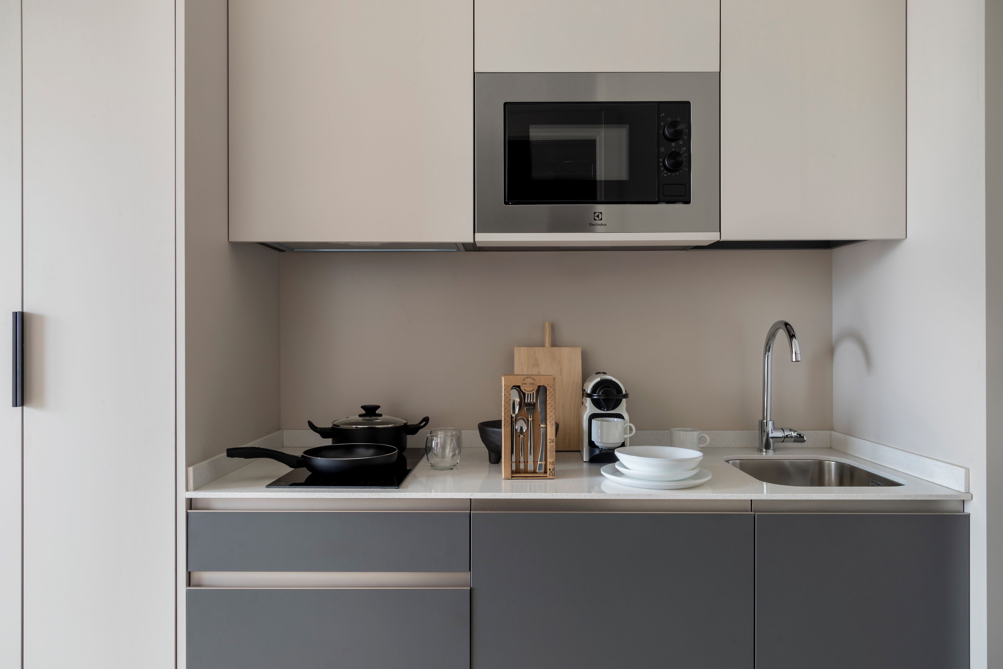 A modern kitchen with a built-in microwave, a sink, and a countertop with various utensils and cookware.
