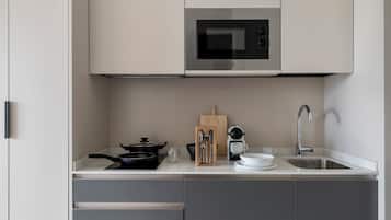 A modern kitchen with a built-in microwave, a sink, and a countertop with various utensils and cookware.