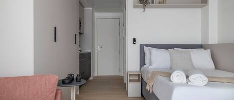 Quarto moderno com cama, uma mesinha com cadeira e um guarda-roupa.