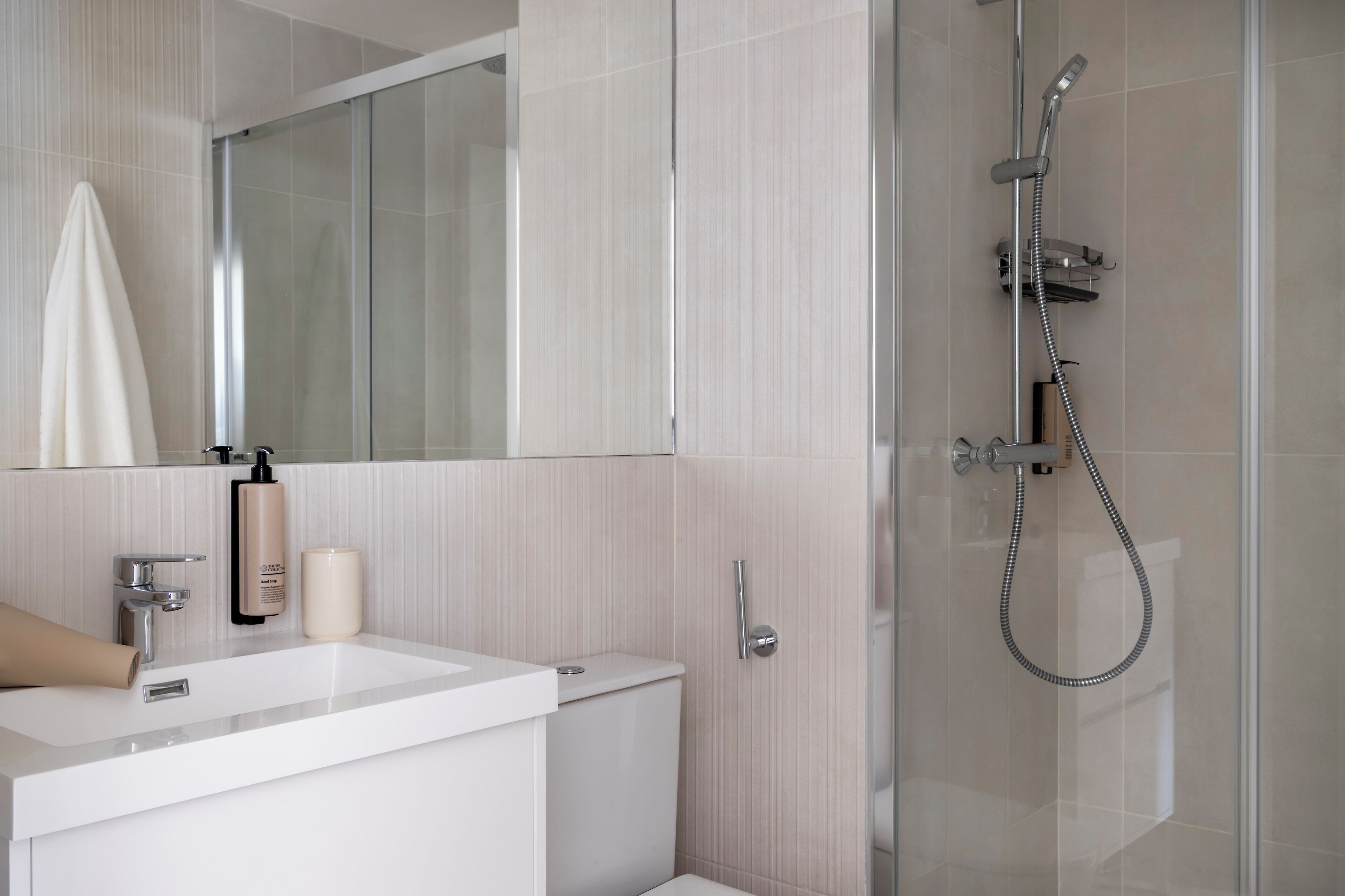 Une salle de bain moderne avec une douche à parois de verre, un lavabo blanc et un miroir au-dessus du lavabo.
