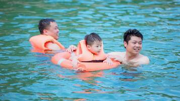 Three people in a body of water, each wearing an orange life jacket.