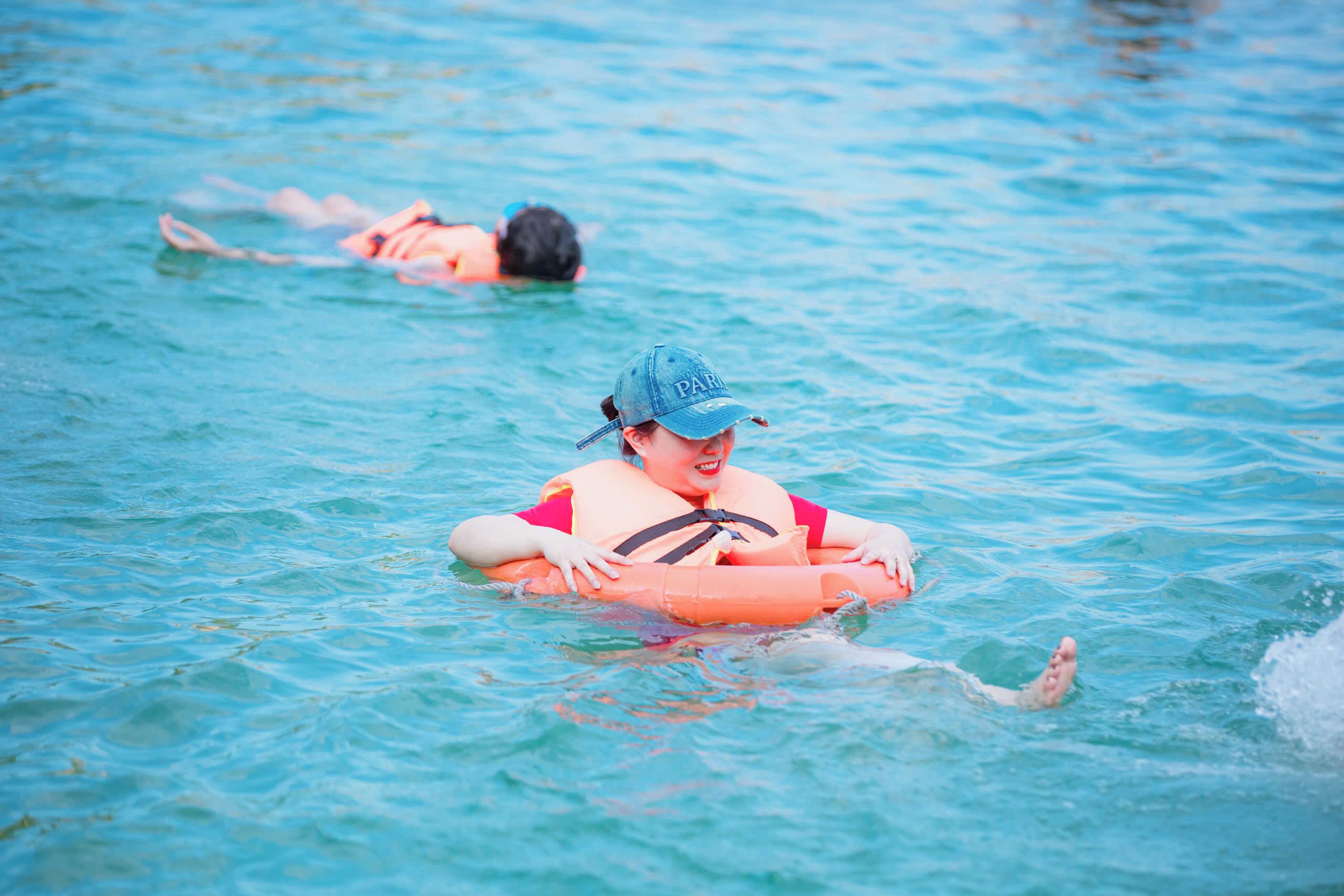 A person in a swimming pool with a life jacket and a cap.