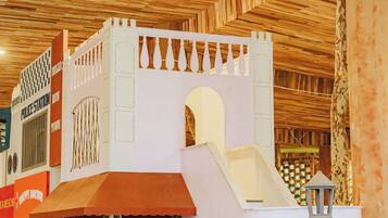 Un área de juegos con una estructura tipo castillo, un tobogán y una cafetería.