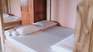 A single bed with white linens and pillows, a wooden headboard, and a wooden partition wall.