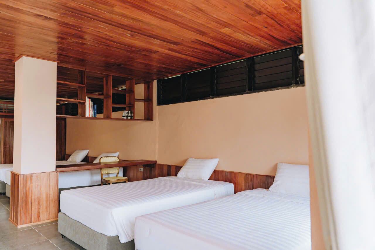 Une chambre d’hôtel avec deux lits, un plafond en bois et un petit bureau avec une chaise.