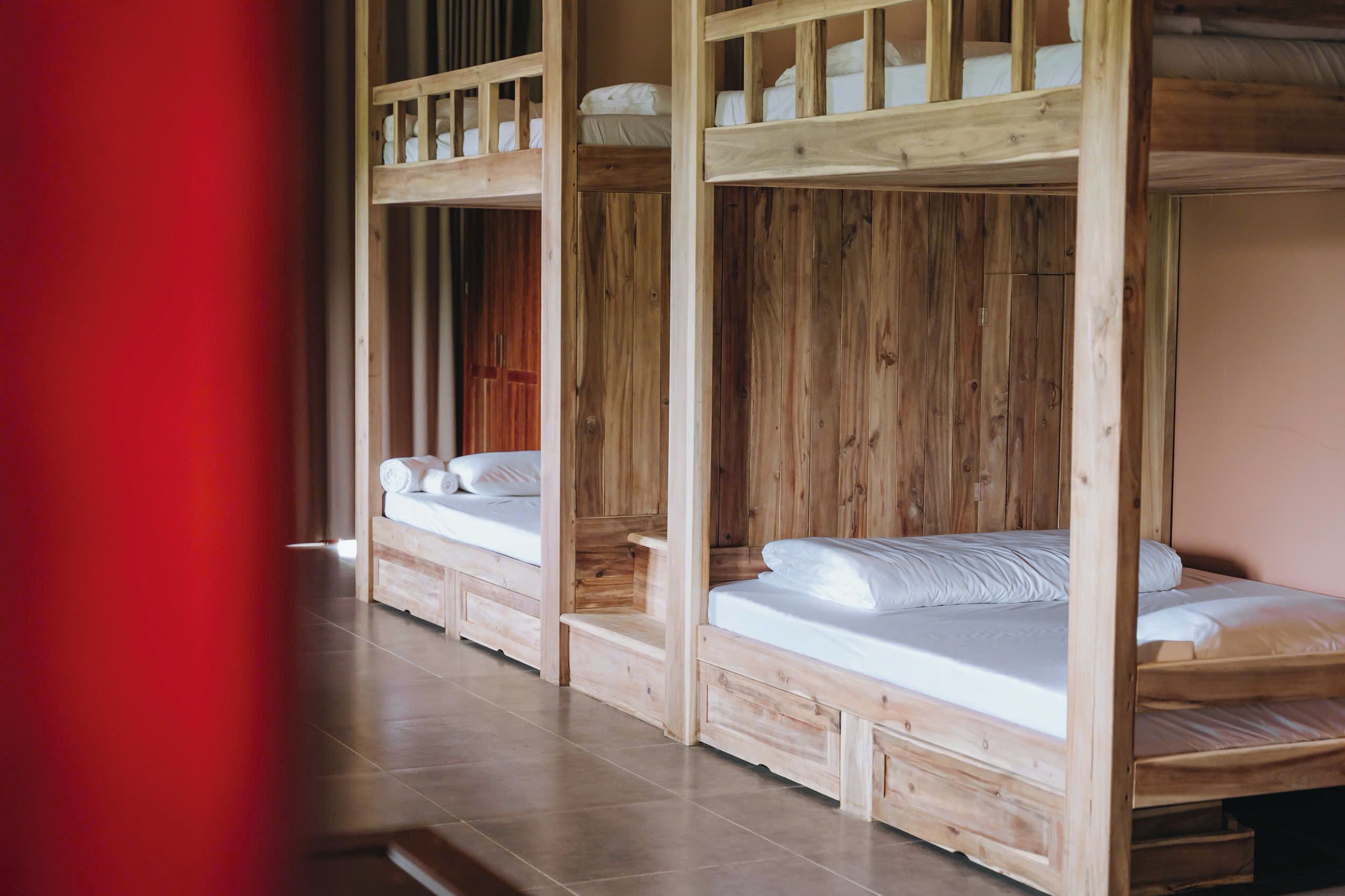 Una habitación con tres literas de madera, cada una con colchón y almohadas.