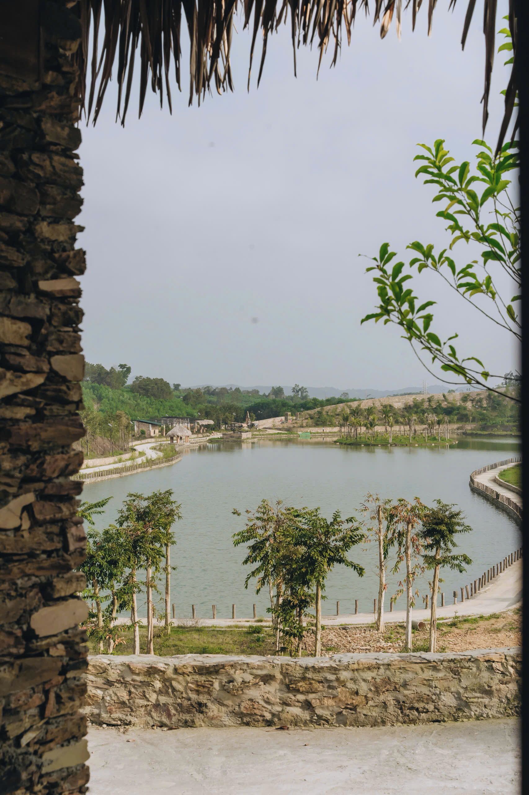Une vue d’un lac, avec un mur de pierres et des arbres au premier plan.