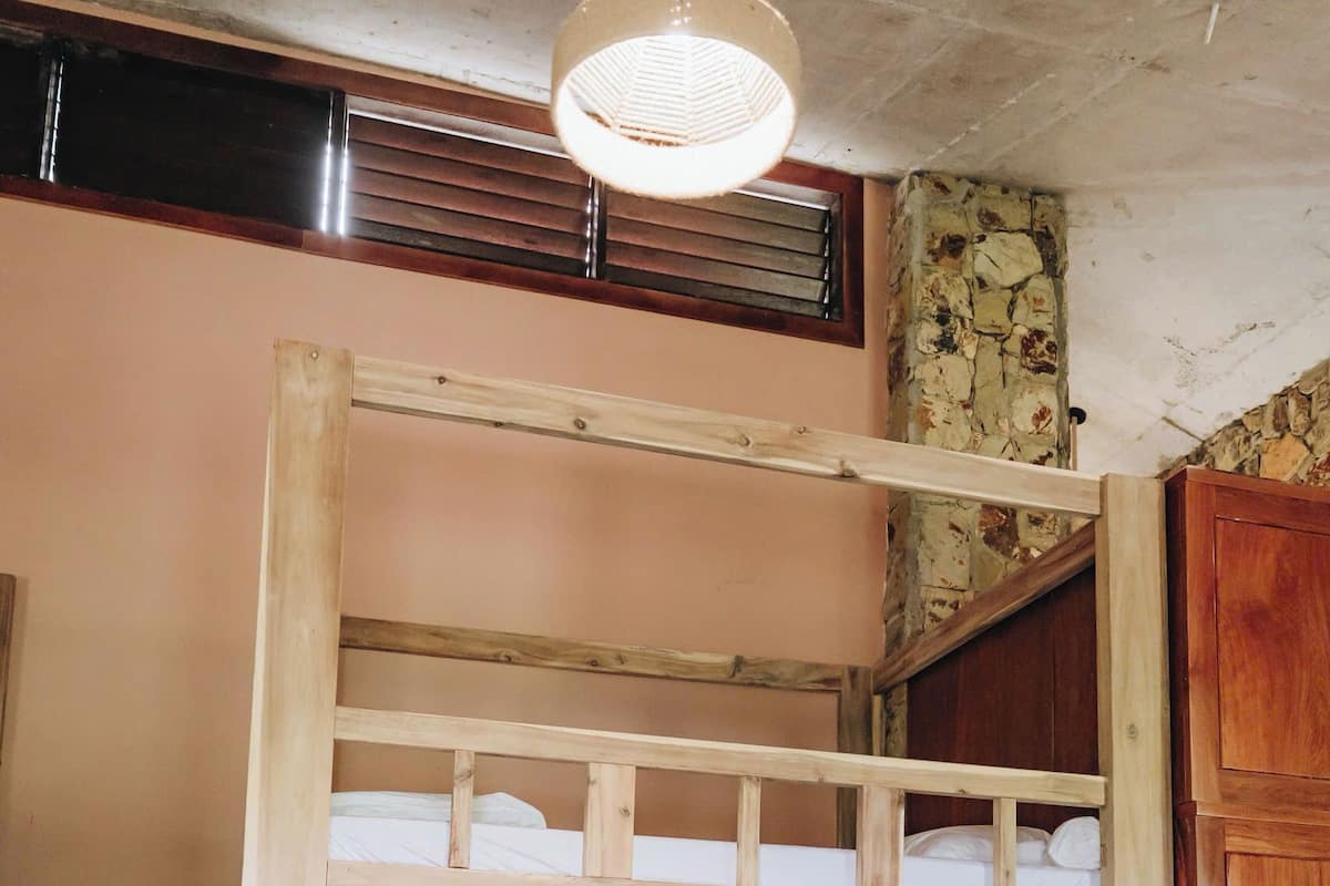 A bunk bed with a wooden frame, a ceiling fan, and a tiled floor.