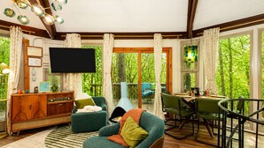 A cozy living room with a television, a wooden cabinet, and a green armchair.
