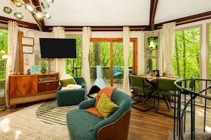 A cozy living room with a television, a wooden cabinet, and a green armchair.