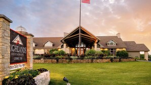 A restaurant with a stone facade, a flagpole with an American flag, and a well-maintained lawn.