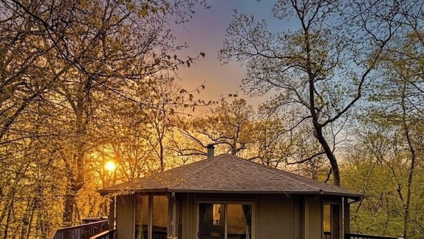 A cabin with a deck, a small porch, and a view of the surrounding trees.