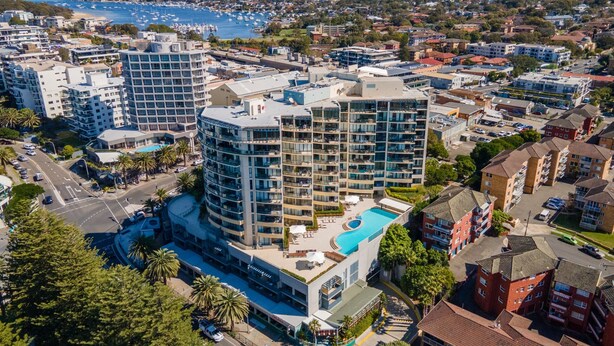 A high-rise hotel with a rooftop pool, surrounded by residential buildings and a marina. - Beachside Studio With Pool and Gym Access (Sydney)