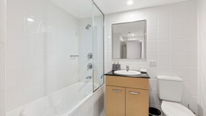 A modern bathroom with a bathtub, a sink, and a toilet. - Beachside Studio With Pool and Gym Access (Sydney)