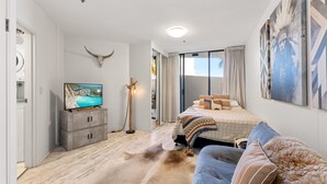 A bedroom with a bed, a TV, a cow skull decoration, and a large window. - Beachside Studio With Pool and Gym Access (Sydney)