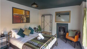 A bedroom with a bed, a painting, a fireplace, a chair, and a mirror. - Stylish & Spacious Retreat in Troedyrhiw | Sleeps 6 | Garden Decking (Troedyrhiw)