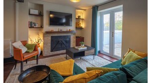 A living room with a fireplace, a sofa, a coffee table, and a television. - Stylish & Spacious Retreat in Troedyrhiw | Sleeps 6 | Garden Decking (Troedyrhiw)