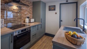 A kitchen with a brick wall, a built-in oven, and a wooden countertop. - Stylish & Spacious Retreat in Troedyrhiw | Sleeps 6 | Garden Decking (Troedyrhiw)