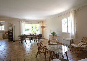 Un amplio salón con una mesa de comedor, sillas, una mesa de centro de vidrio y un radiador.