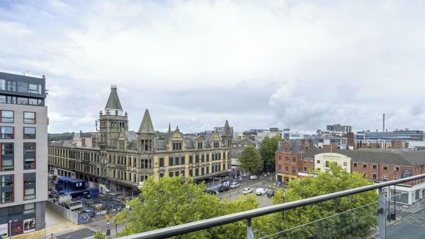 Un edificio histórico con una torre destacada y un edificio moderno contiguo.