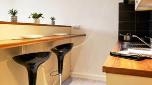 Una cocina moderna con encimera de madera, taburetes negros y pileta de acero inoxidable.