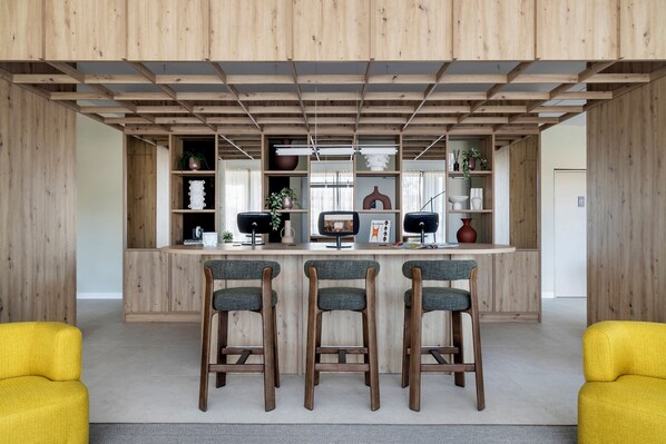 Une cuisine moderne avec des meubles en bois, un îlot central doté de tabourets et une bibliothèque intégrée.