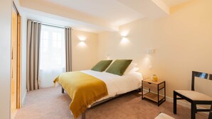 A bedroom with a bed, a chair, a nightstand, and a window with curtains. - Tenda room (Douzy)