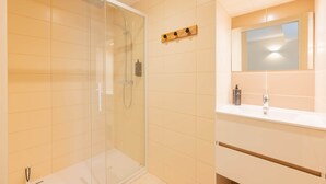 A modern bathroom with a glass-enclosed shower, a white sink, and a mirror above it. - Tenda room (Douzy)