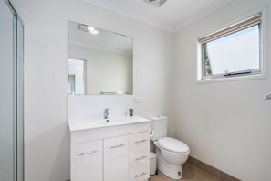A modern bathroom with a white sink, mirror, and toilet. - Relaxed 2br, 2bth Apartment With Balcony & Parking (Canberra)