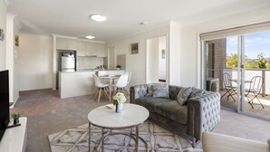 A modern apartment with a kitchen, dining area, living room, and balcony. - Relaxed 2br, 2bth Apartment With Balcony & Parking (Canberra)